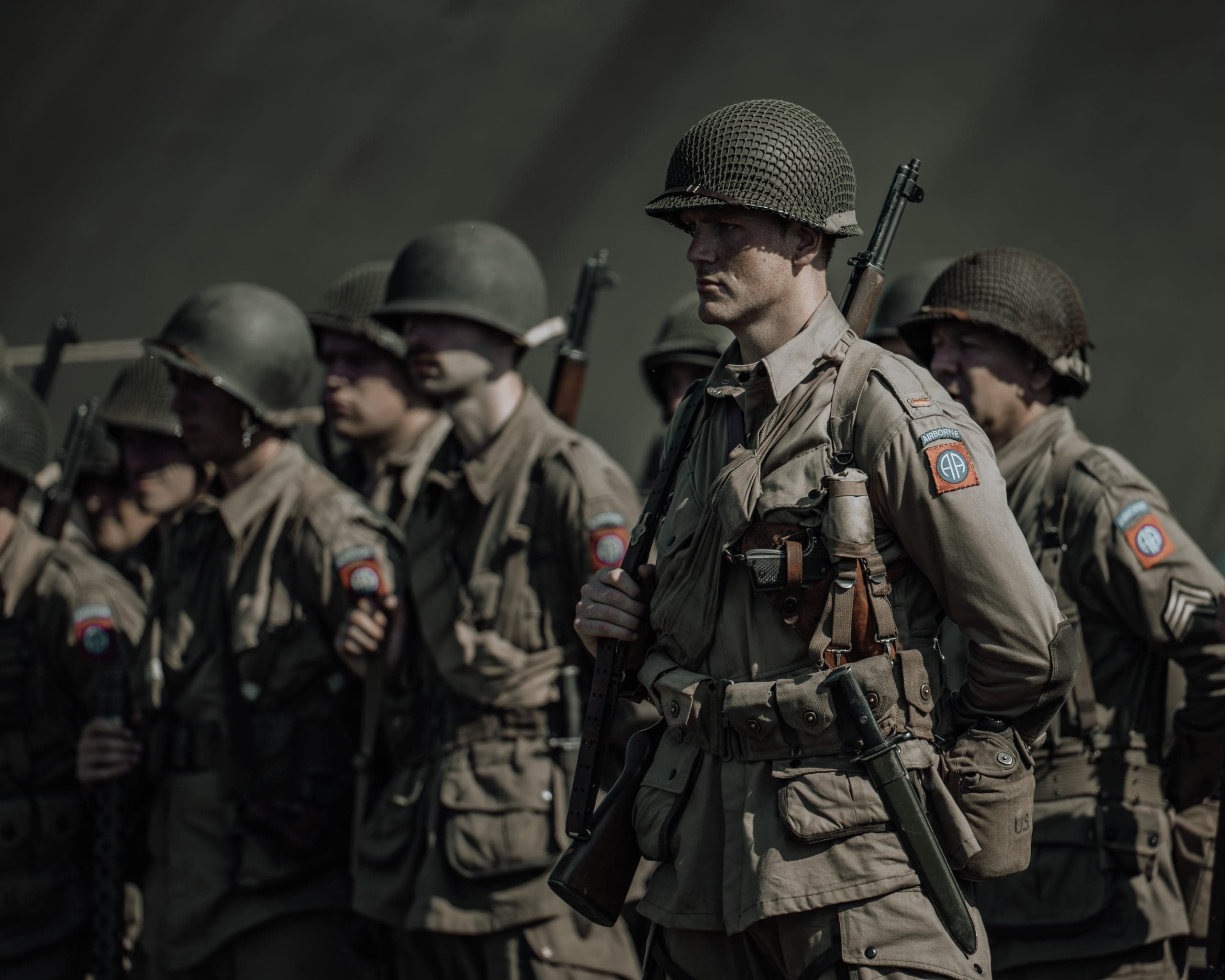 Rij 82nd Airborne paratroopers in formatie met geschouderde geweren, gedempt palet en strakke lijncompositie